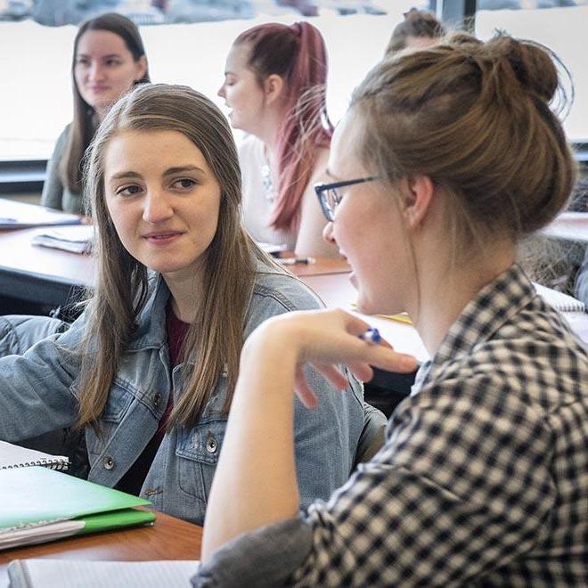 Happy female students having a conversation in class